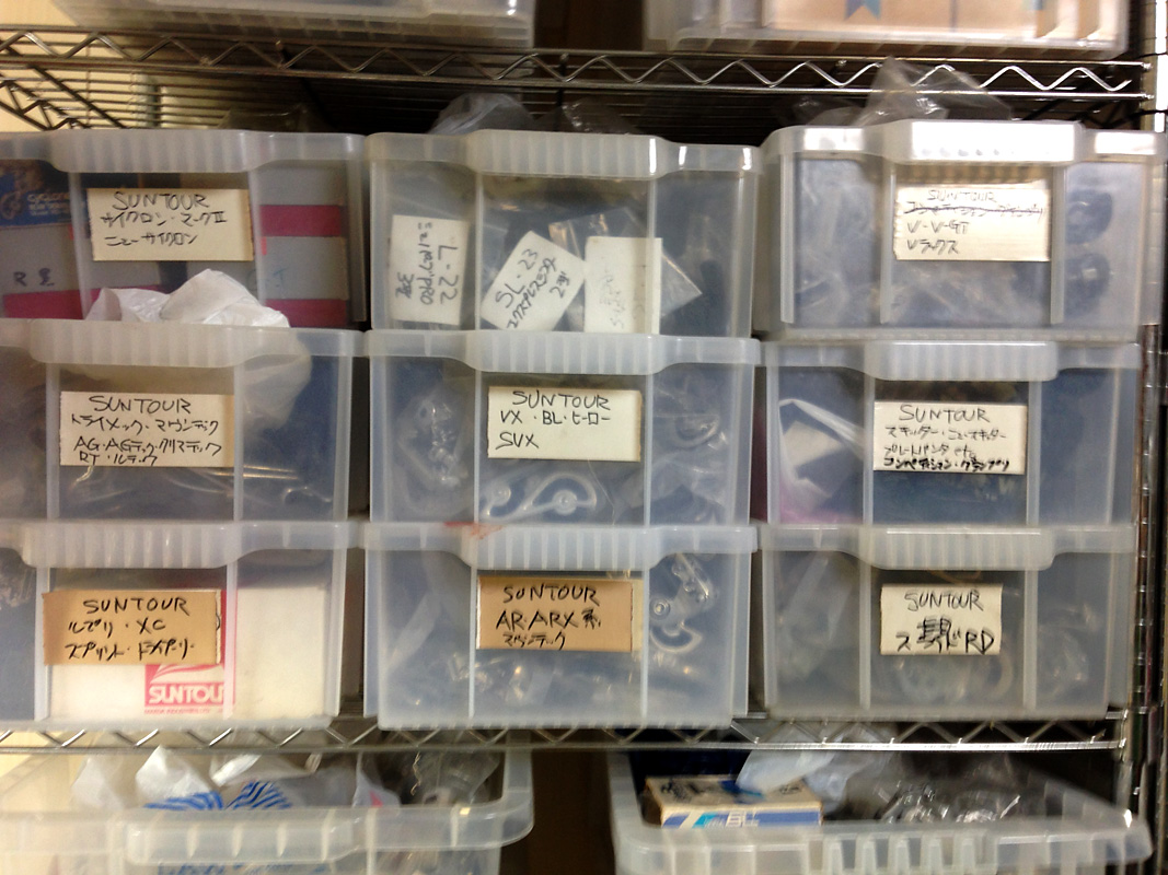 many properly labeled plastic boxes bneeath the roof of his house contain Mr. Sasaki's derailleur treasures 